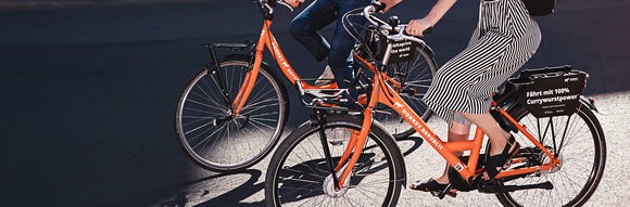 Two people riding side by side on Donkey Republic bikes 